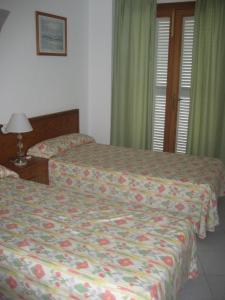 two beds in a hotel room with green curtains at Holiday homes Bonamar in Colònia de Sant Jordi