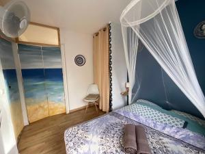 a bedroom with a bed with a canopy and a window at BUNGALOWS LES VAGUES ABONDES in Sainte-Anne