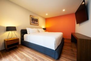 ein Schlafzimmer mit einem weißen Bett und einer orangefarbenen Wand in der Unterkunft Capitalia - Apartments - CÉFIRO CINCO in Mexiko-Stadt
