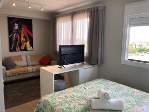 um quarto com uma cama e uma secretária com uma televisão em Loft 1303 Maxplaza, Encantador, piscina, garagem em Canoas