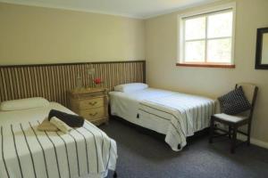 a bedroom with two beds and a chair and a window at Blackfern cottage in Ongarue