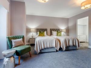 a bedroom with two beds and a green chair at Fairview in Penicuik