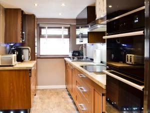 a kitchen with wooden cabinets and a sink at The Cart House in Merthyr Cynog