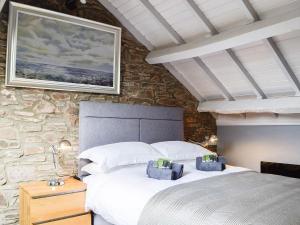 a bedroom with a bed and a stone wall at The Cart House in Merthyr Cynog