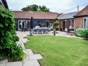 a patio with tables and chairs in a yard at Lodge Farm Barn in South Walsham