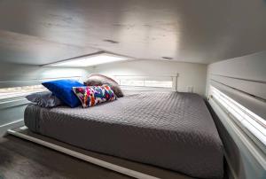 a bed in a small room with two windows at Cozy modern tiny home near ZION & private deck in Apple Valley