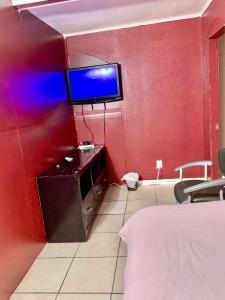 a room with a red wall with a tv on the wall at The Ugly House in Houston