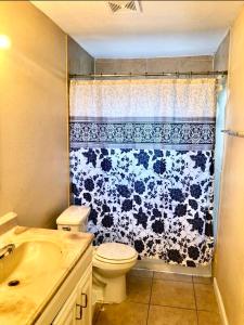 a bathroom with a toilet and a black and white shower curtain at The Ugly House in Houston