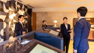 a group of people standing around a counter in a lobby at JR-East Hotel Mets Akabane in Tokyo