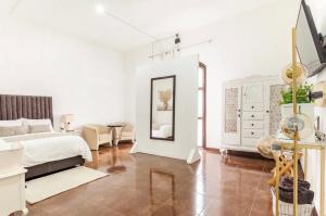 a white bedroom with a bed and a mirror at Suite Copal in Tecozautla