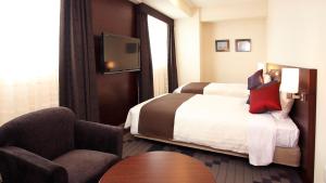 a hotel room with a bed and a chair at JR-East Hotel Mets Yokohama Tsurumi in Yokohama