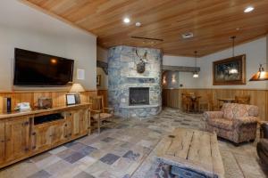 a living room with a stone fireplace and a flat screen tv at Jackpine Lodge by Summit County Mountain Retreats in Keystone