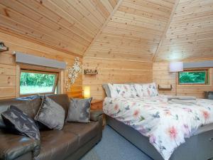 1 dormitorio con 1 cama y 1 sofá en una cabaña de madera en Coot Roundhouse - Uk33890, en Cullompton