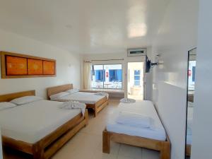 a room with three beds and a window at Hotel Portoalegre in Coveñas