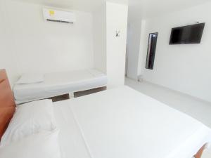 Habitación blanca con cama y escritorio. en Hotel Portoalegre, en Coveñas