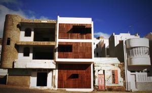 a tall white building with a red brick at Paz Apartment in Mindelo