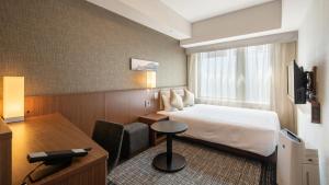 una camera d'albergo con letto e scrivania di HOTEL UNIZO Kyoto Karasuma Oike a Kyoto