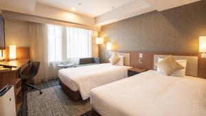 京都市にあるホテルユニゾ京都烏丸御池のベッド2台とデスクが備わるホテルルームです。