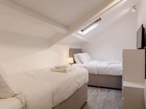 2 camas en una habitación con paredes blancas en The Barn-uk32860, en Alltwen