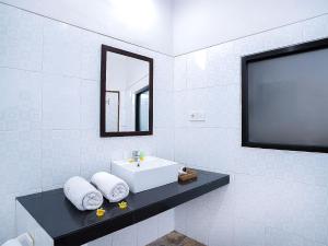 ein weißes Badezimmer mit einem Waschbecken und einem Flachbild-TV in der Unterkunft Amanlane Suite Seminyak Managed by ARM Hospitality in Seminyak + 22 Fotos