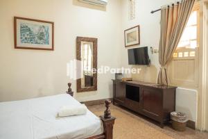 ジョグジャカルタにあるMonginsidi Guest House Syariah Malioboro Yogyakarta Mitra RedDoorzのベッドルーム(ベッド1台、テレビ、鏡付)