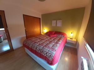 a bedroom with a large bed with a red bedspread at Ushuaia JAUKE Departamentos in Ushuaia