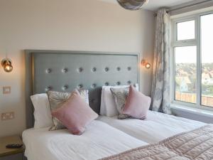 a bedroom with a bed with pink pillows and a window at Crows Nest in Bridlington