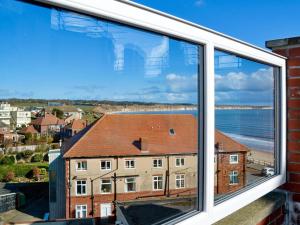 a window with a view of the ocean and buildings at Crows Nest in Bridlington
