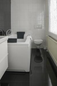 
a white toilet sitting next to a bath tub in a bathroom at Hotel Zwanenburg Amsterdam Airport in Zwanenburg
