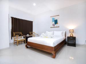 ein Schlafzimmer mit einem Bett, zwei Tischen und einem Stuhl in der Unterkunft Amanlane Suite Seminyak Managed by ARM Hospitality in Seminyak