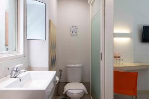 a bathroom with a sink and a toilet and a mirror at Cleo Hotel Basuki Rahmat in Surabaya