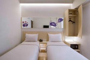 2 Betten in einem kleinen Zimmer mit lila Akzenten in der Unterkunft Cleo Hotel Basuki Rahmat in Surabaya