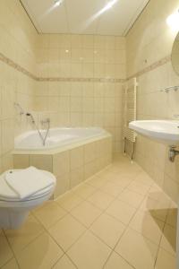 a bathroom with a tub and a toilet and a sink at Hotel Zwanenburg Amsterdam Airport in Zwanenburg