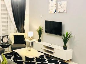 a living room with a tv on a white wall at Villa Pool Kepala Batas in Kampong Hilir