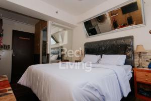 a bedroom with a large white bed and a mirror at RedLiving Apartemen Gunung Putri Square - TOP Room in Parungtandjung
