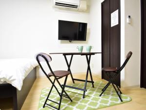 um quarto com uma mesa e duas cadeiras e uma televisão em Regariain - Vacation STAY 84627 em Okayama