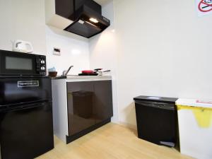 eine Küche mit einem schwarzen Kühlschrank und einer Mikrowelle in der Unterkunft Regariain - Vacation STAY 84627 in Okayama