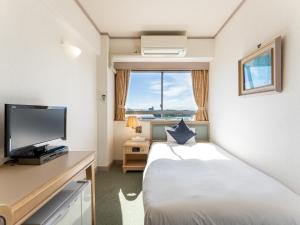 a hotel room with a bed and a television at Tabist Hotel Ginga Kisarazu in Kisarazu