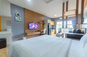 1 dormitorio con 1 cama blanca grande y TV en Eastpana Hotel - SHA Extra Plus, en Si Racha