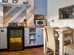 a kitchen with a stove and a table with a microwave at Plum Cottage in Castle Cary