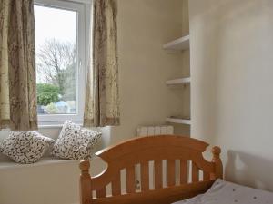 ein Schlafzimmer mit einem Kinderbett und einem Fenster in der Unterkunft Plum Cottage in Castle Cary