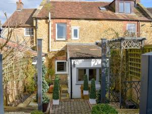 una vieja casa de ladrillo con un garaje blanco en Plum Cottage, en Castle Cary