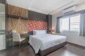 a bedroom with a bed and a desk and a chair at Eastpana Hotel - SHA Extra Plus in Si Racha