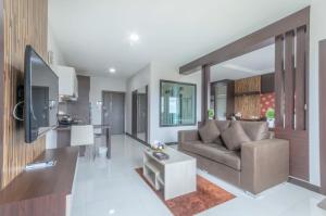 a living room with a couch and a kitchen at Eastpana Hotel - SHA Extra Plus in Si Racha