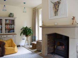 a living room with a fireplace with a cow on the wall at Woodland View in Whitewell