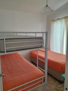 - une chambre avec 2 lits superposés et des draps orange dans l'établissement Cabanas bahia inglesa, à Bahia Inglesa