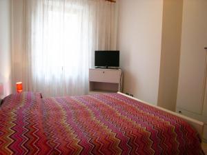 - une chambre avec un lit, une télévision et une fenêtre dans l'établissement Villa Coloatto, à Grado
