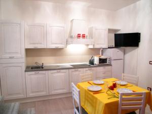 une cuisine avec des placards blancs et une table jaune avec des chaises dans l'établissement Villa Coloatto, à Grado