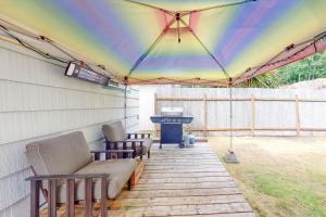 um pátio com uma tenda arco-íris, cadeiras e comodidades para churrascos. em Bay Bliss #2 em Reedsport