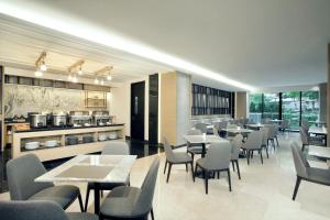 a restaurant with tables and chairs and a kitchen at Somerset Sudirman Jakarta in Jakarta
